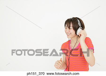 Close-up of a young woman listening to music View Large Photo Image Stock Image - Close-up of a young woman listening to music. Fotosearch