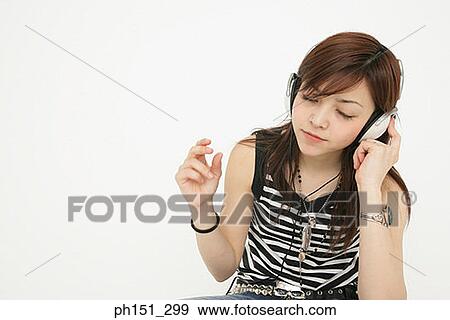 Close-up of a young woman listening to music View Large Photo Image Stock Photo - Close-up of a young woman listening to music. Fotosearch