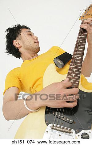 Low angle view of a young man playing an electric guitar View Large Photo Image Picture - Low angle view of a young man playing an electric guitar. Fotosearch