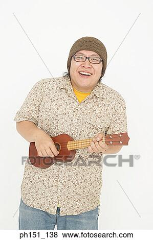 Stock Photo - Portrait of a mid adult man playing a toy guitar and smiling. Fotosearch