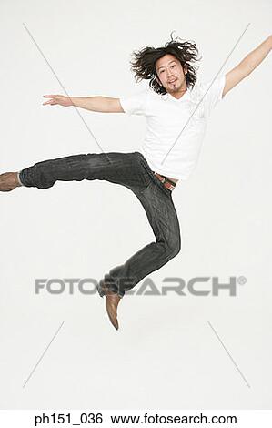 Portrait of a young man jumping with his arms outstretched View Large Photo Image Stock Photograph - Portrait of a young man jumping with his arms outstretched. Fotosearch