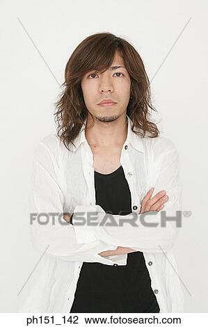 Stock Image - Portrait of a young man standing with his arms crossed. Fotosearch