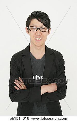 Stock Photograph - Portrait of a young man standing with his arms crossed and smiling. Fotosearch