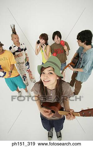 Stock Photo - Portrait of a young woman and her friends playing musical instruments. Fotosearch