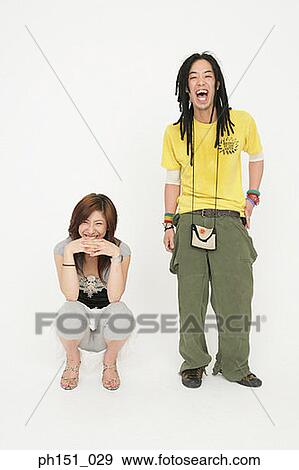 Stock Photo - Portrait of a young woman crouching with a young man standing beside her. Fotosearch