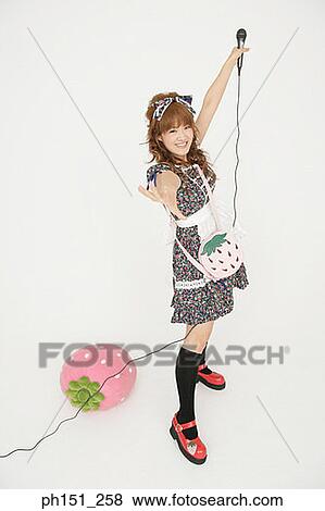 Stock Photo - Portrait of a young woman holding a microphone and smiling. Fotosearch