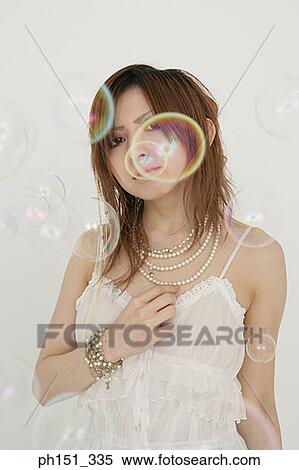 Portrait of a young woman standing with soap bubbles in front of her View Large Photo Image Stock Photography - Portrait of a young woman standing with soap bubbles in front of her. Fotosearch
