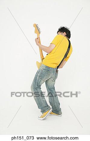 Rear view of a young man playing an electric guitar View Large Photo Image Stock Image - Rear view of a young man playing an electric guitar. Fotosearch