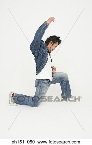 Side profile of a young man kneeling on the floor with one hand raised View Large Photo Image Stock Image - Side profile of a young man kneeling on the floor with one hand raised. Fotosearch