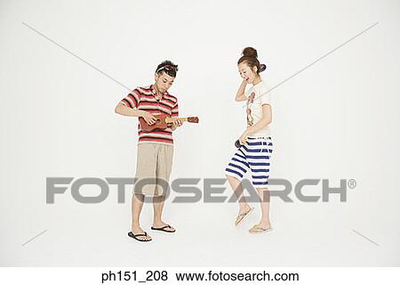 Side profile of a young woman dancing and a young man playing a toy guitar View Large Photo Image Stock Photo - Side profile of a young woman dancing and a young man playing a toy guitar. Fotosearch