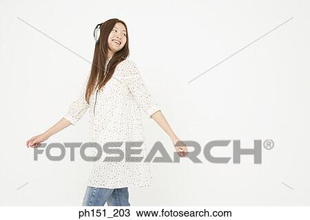 Side profile of a young woman listening to music on headphones View Large Photo Image Stock Image - Side profile of a young woman listening to music on headphones. Fotosearch