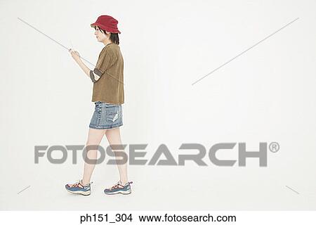 Side profile of a young woman walking and using a mobile phone View Large Photo Image Picture - Side profile of a young woman walking and using a mobile phone. Fotosearch