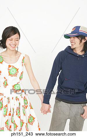 Young couple standing and holding hands View Large Photo Image Stock Image - Young couple standing and holding hands. Fotosearch