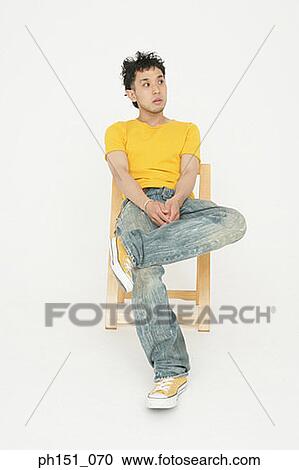 Young man sitting on a wooden chair with his legs crossed View Large Photo Image Stock Image - Young man sitting on a wooden chair with his legs crossed. Fotosearch