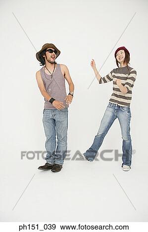 Stock Photo - Young man standing with a young woman and sticking out his tongue. Fotosearch