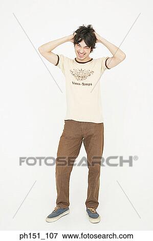 Young man tousling his hair and smiling View Large Photo Image Stock Photo - Young man tousling his hair and smiling. Fotosearch