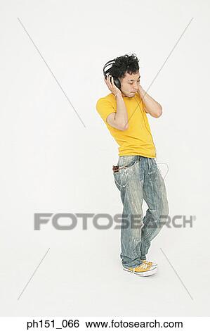 Stock Photograph - Young man wearing headphones and listening to music. Fotosearch