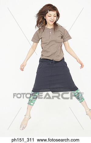 Stock Image - Young woman jumping and smiling. Fotosearch