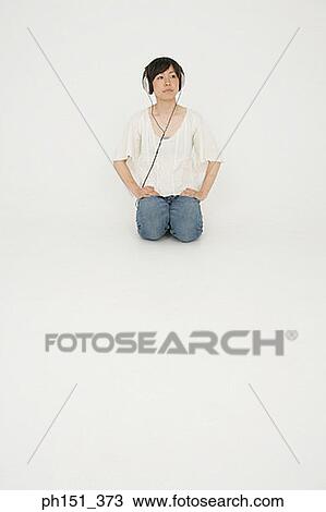 Young woman kneeling and listening to music View Large Photo Image Stock Image - Young woman kneeling and listening to music. Fotosearch