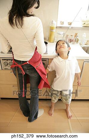 Stock Photo - Boy standing beside his mother in the kitchen. Fotosearch