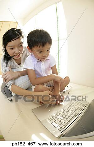 Close-up of a boy and his sister sitting in front of a laptop View Large Photo Image Stock Photo - Close-up of a boy and his sister sitting in front of a laptop. Fotosearch