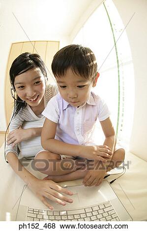 Stock Photo - Close-up of a boy and his sister sitting in front of a laptop. Fotosearch