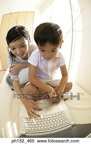 Stock Photography - Close-up of a boy and his sister sitting in front of a laptop. Fotosearch