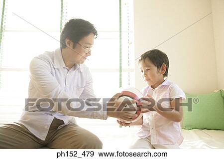 Stock Photo - Close-up of a boy taking a soccer ball from his father. Fotosearch