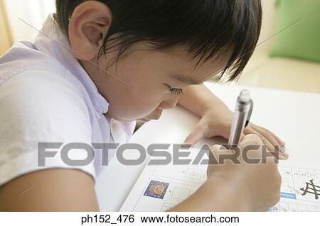 Close-up of a boy writing in a book View Large Photo Image Stock Photograph - Close-up of a boy writing in a book. Fotosearch