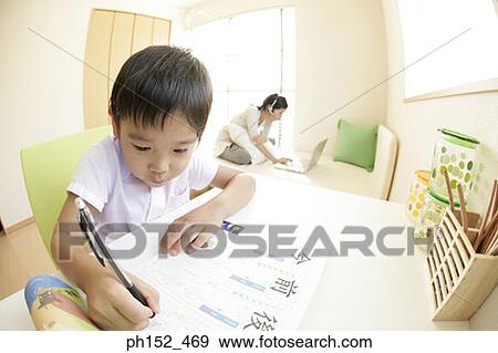 Close-up of a boy writing on a sheet of paper with his sister using a laptop in the background View Large Photo Image Stock Photo - Close-up of a boy writing on a sheet of paper with his sister using a laptop in the background. Fotosearch