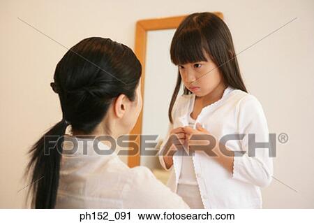 Close-up of a girl buttoning her cardigan in front of her mother View Large Photo Image Stock Image - Close-up of a girl buttoning her cardigan in front of her mother. Fotosearch