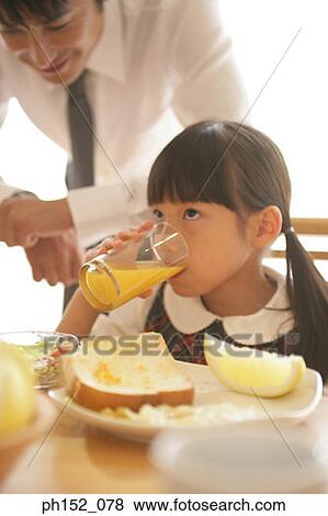 Close-up of a girl drinking orange juice with her father standing behind her View Large Photo Image Stock Photo - Close-up of a girl drinking orange juice with her father standing behind her. Fotosearch