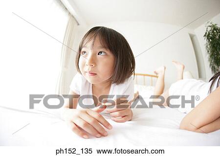 Close-up of a girl lying on the bed with her sister lying beside her View Large Photo Image Stock Photography - Close-up of a girl lying on the bed with her sister lying beside her. Fotosearch