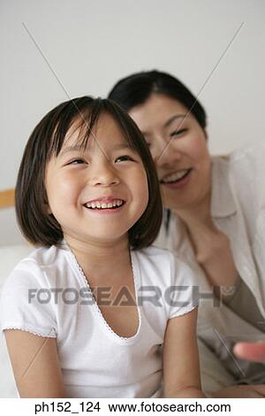Close-up of a girl with her mother smiling View Large Photo Image Picture - Close-up of a girl with her mother smiling. Fotosearch