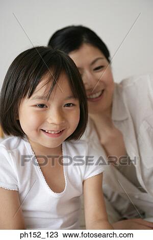 Stock Image - Close-up of a girl with her mother smiling. Fotosearch