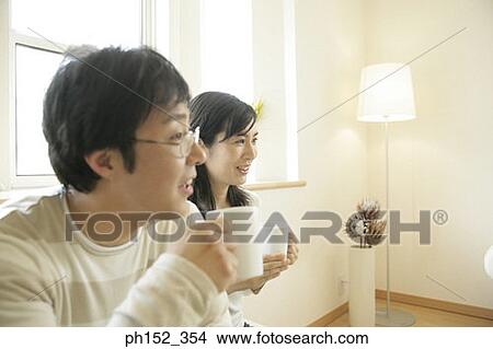 Close-up of a mid adult couple holding cups of coffee View Large Photo Image Picture - Close-up of a mid adult couple holding cups of coffee. Fotosearch