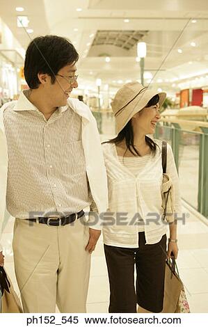 Close-up of a mid adult couple smiling in a shopping mall View Large Photo Image Stock Photography - Close-up of a mid adult couple smiling in a shopping mall. Fotosearch