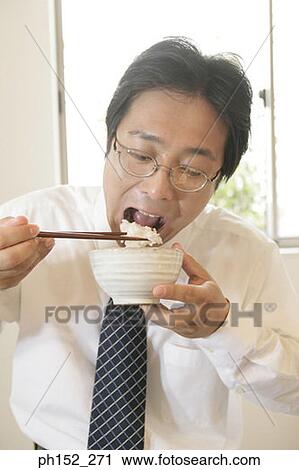 Stock Image - Close-up of a mid adult man eating rice. Fotosearch
