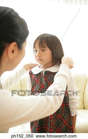 Stock Image - Close-up of a mid adult woman adjusting her daughter's school uniform collar. Fotosearch