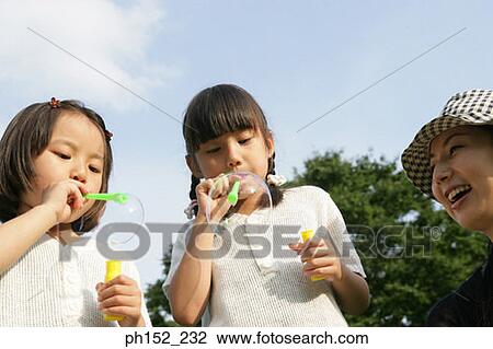 Close-up of a mid adult woman and her two daughters blowing bubbles View Large Photo Image Stock Image - Close-up of a mid adult woman and her two daughters blowing bubbles. Fotosearch
