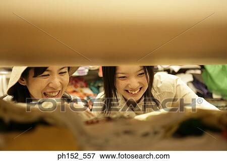 Close-up of a mid adult woman and her daughter in a clothing store View Large Photo Image Stock Photo - Close-up of a mid adult woman and her daughter in a clothing store. Fotosearch