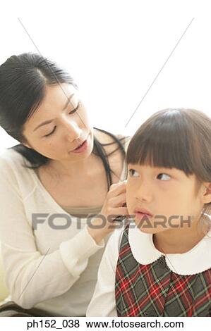 Stock Photo - Close-up of a mid adult woman brushing her daughter's hair. Fotosearch