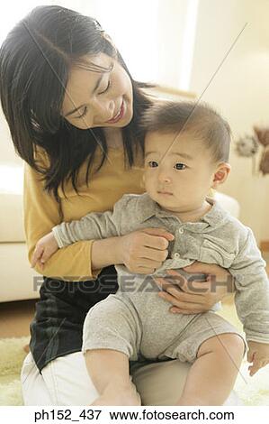 Stock Photo - Close-up of a mid adult woman holding her son. Fotosearch