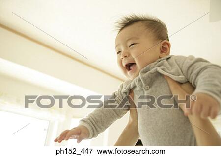 Stock Photo - Close-up of a mid adult woman's hand lifting a baby boy. Fotosearch