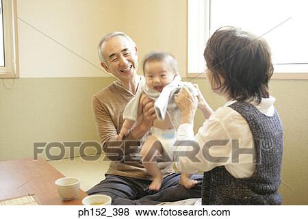 Stock Photo - Close-up of a senior couple dressing their grandson. Fotosearch