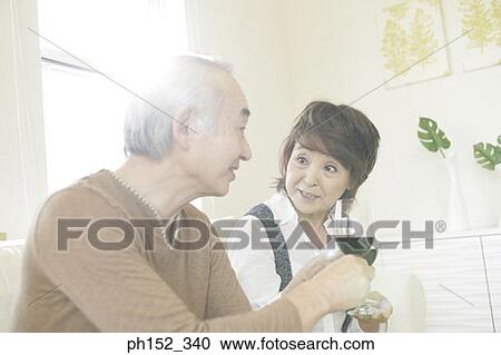 Close-up of a senior couple sitting on a couch and toasting glasses of red wine View Large Photo Image Stock Image - Close-up of a senior couple sitting on a couch and toasting glasses of red wine. Fotosearch