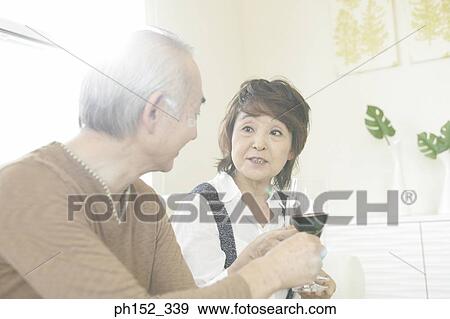 Close-up of a senior couple sitting on a couch and toasting glasses of red wine View Large Photo Image Stock Photo - Close-up of a senior couple sitting on a couch and toasting glasses of red wine. Fotosearch