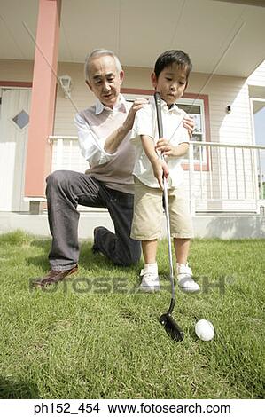 Close-up of a senior man teaching his grandson how to play golf View Large Photo Image Picture - Close-up of a senior man teaching his grandson how to play golf. Fotosearch