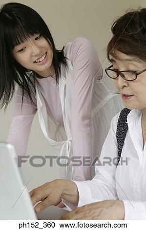 Close-up of a senior woman using a laptop with her granddaughter standing beside her View Large Photo Image Stock Image - Close-up of a senior woman using a laptop with her granddaughter standing beside her. Fotosearch