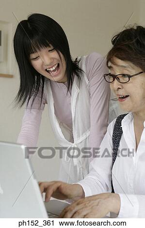 Close-up of a senior woman using a laptop with her granddaughter standing beside her View Large Photo Image Stock Image - Close-up of a senior woman using a laptop with her granddaughter standing beside her. Fotosearch